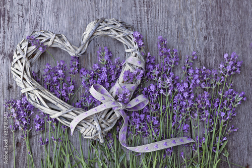 Lavender flowers  with wicker heart on wooden background 