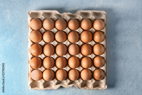 Carton pack with raw chicken eggs on color table © Pixel-Shot