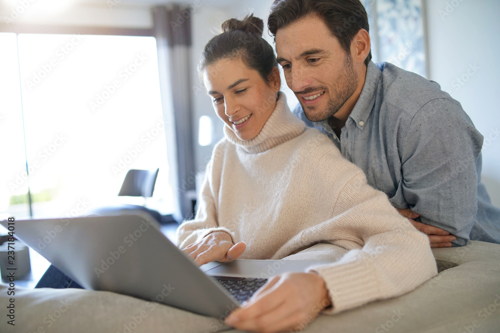 Gorgeous couple looking at computer at home Gorgeous couple looking at computer at home