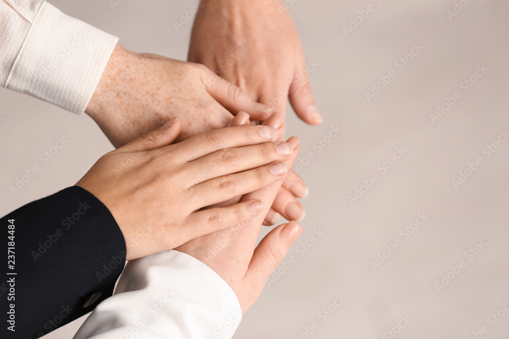 People putting hands together on light background People putting hands together on light background