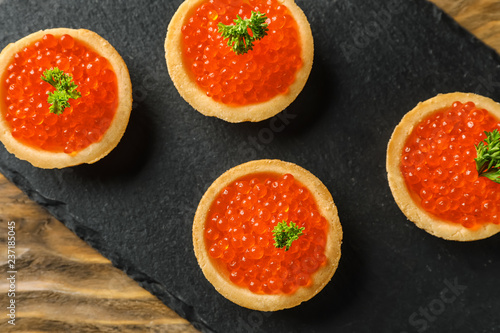 Delicious canapes with red caviar on slate plate