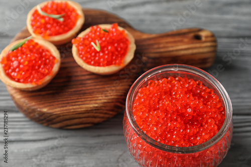 Jar with delicious red caviar on wooden table
