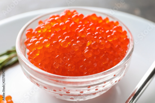 Bowl with delicious red caviar on plate, closeup