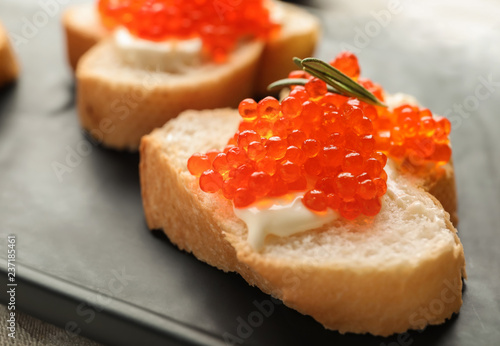 Delicious sandwiches with red caviar on plate, closeup