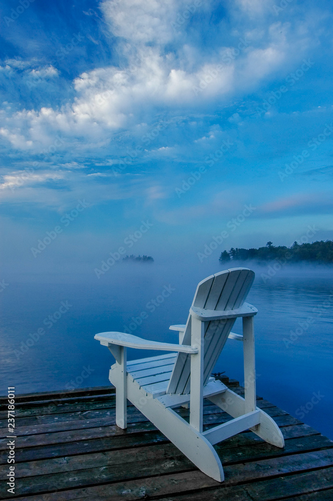 white deck chair on the dock, overlooking mist covered lake white deck chair on the dock, overlooking mist covered lake