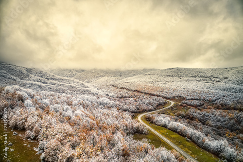Aerial view of snowy forest with a road in the area of Vermio in northern Greece.  Captured from above with a drone. photo