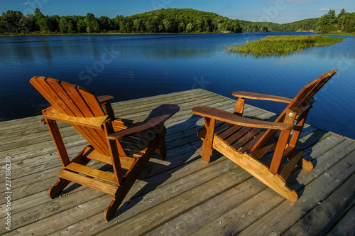 wooden Muskoka chairs on dock, overlooking deep blue lake
