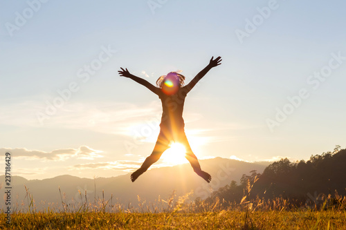 Silhouette of happy child jumping playing on mountain at sunset time