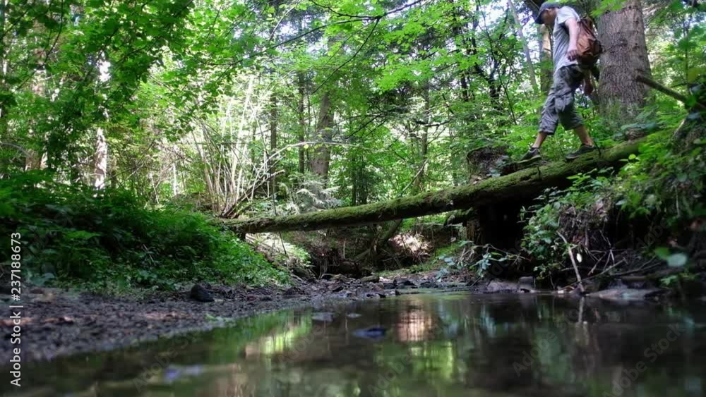 Alone man in wild forest passes across the river. Travel and adventure concept Alone man in wild forest passes across the river. Travel and adventure concept