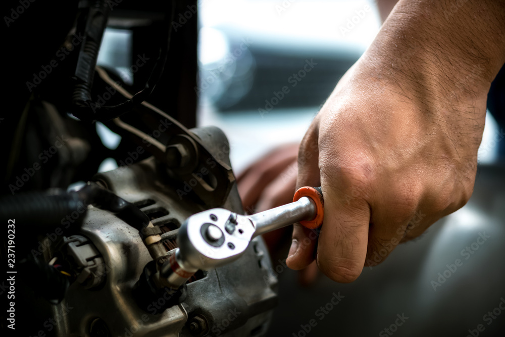 Image is close up.Car mechanic using a wrench Dynamo Auto Repair..