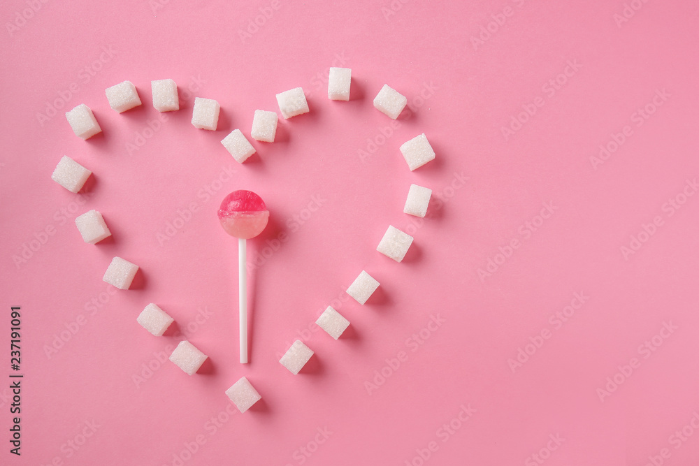Creative composition made with white sugar cubes and lollipop on color background
