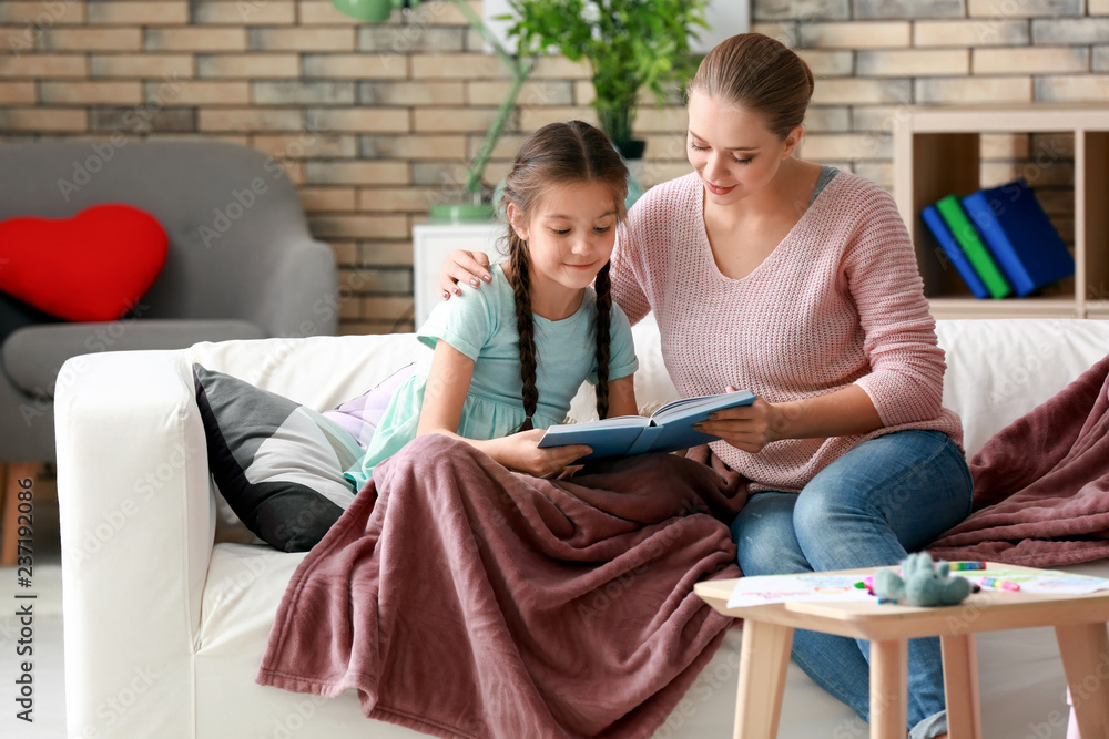Cute girl with mother reading book at home Cute girl with mother reading book at home