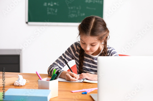 Canvas Print Cute girl doing homework in classroom