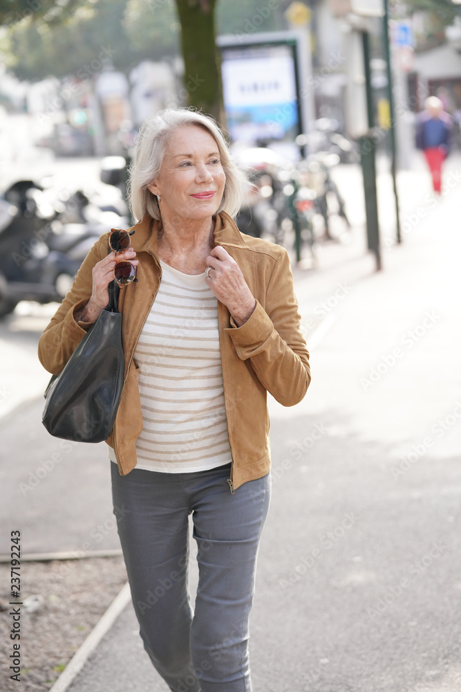 Fototapeta premium Attractive senior woman walking through town