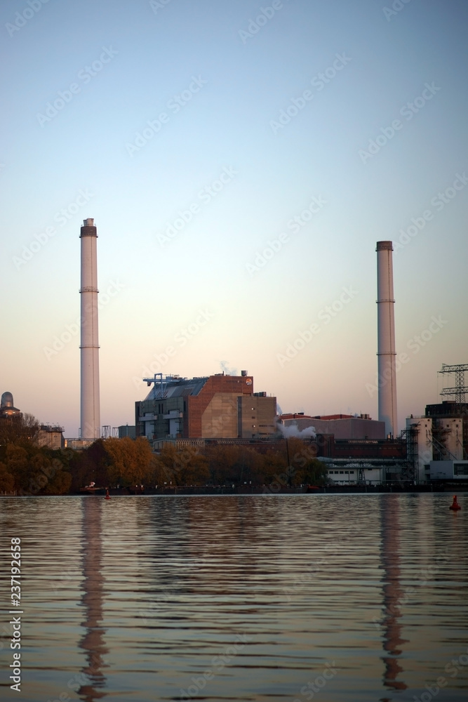 Obraz premium Altes Glaswerk Friedrichshain / Die Schornsteine und Industriegebäude des alten Glaswerkes Friedrichshain auf der Halbinsel Stralau reflektieren sich im Wasser.