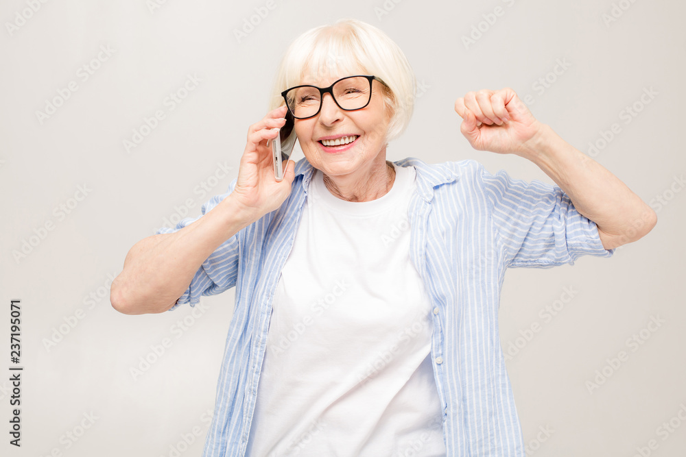 Phone conversation. Positive happy aged woman smiling while talking on the phone, isolated over white background. Phone conversation. Positive happy aged woman smiling while talking on the phone, isolated over white background.