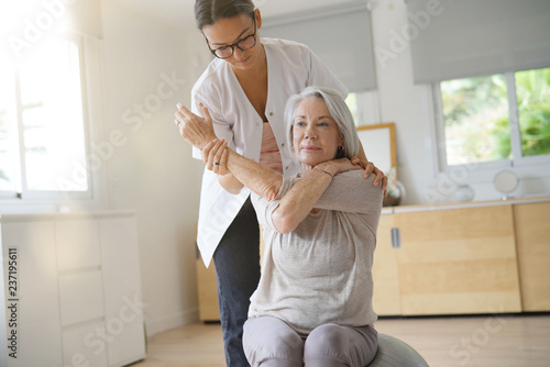 Senior woman exercising with her physiotherapist and swiss ball photo