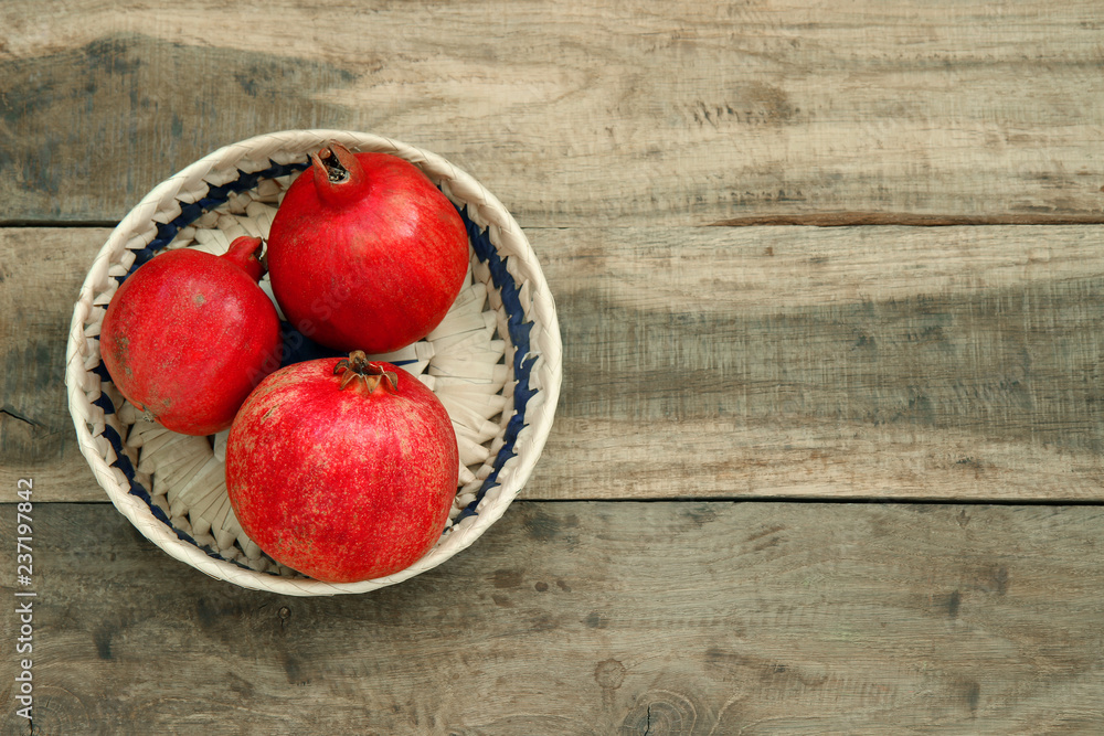 red pomegranates in a basket on a wooden table red pomegranates in a basket on a wooden table