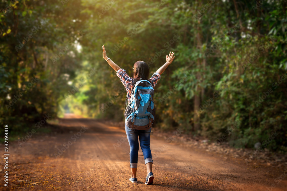 Woman traveler with backpack walking on path in the tropical forest.