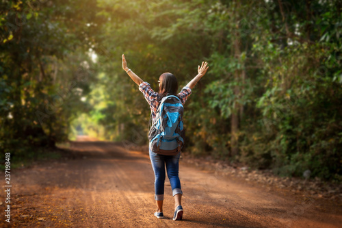 Woman traveler with backpack walking on path in the tropical forest.