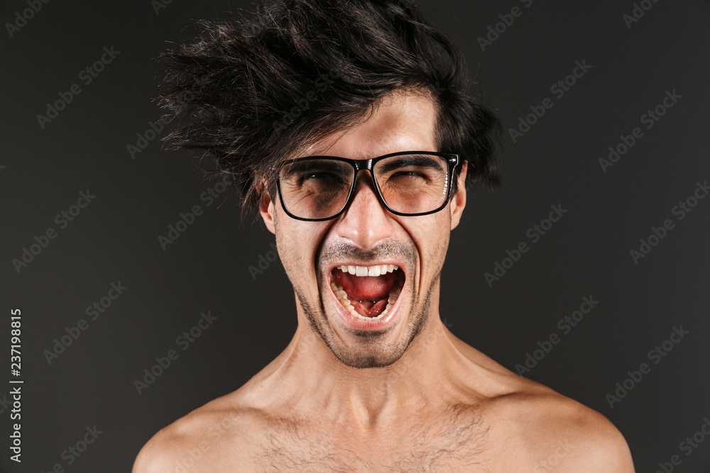Screaming young man posing isolated over dark wall background. Screaming young man posing isolated over dark wall background.