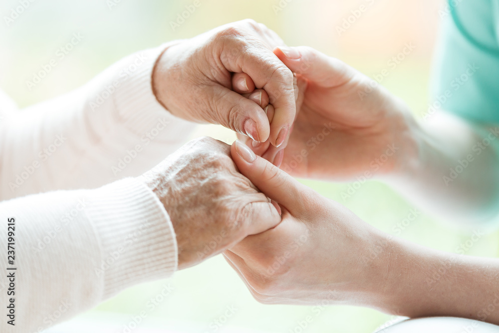 Closeup of the hands of a young woman holding hands of an elderly lady - obrazy, fototapety, plakaty 