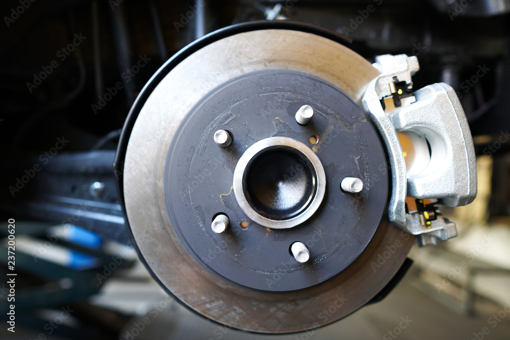 Close up of Brake Disc of the vehicle for repair.Automobile mechanic in process of new tire replacement.Car brake repairing in garage.Car Service and technician concept. Close up of Brake Disc of the vehicle for repair.Automobile mechanic in process of new tire replacement.Car brake repairing in garage.Car Service and technician concept.