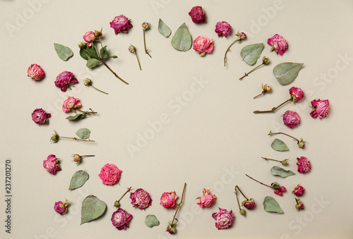 Frame made of beautiful dry roses on light background