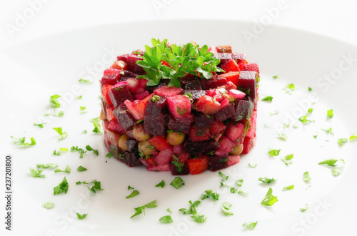 Salad with beetroot, carrot, potato, pickled cucumber, onion, apple, pea, and herbs decorated with parsley 