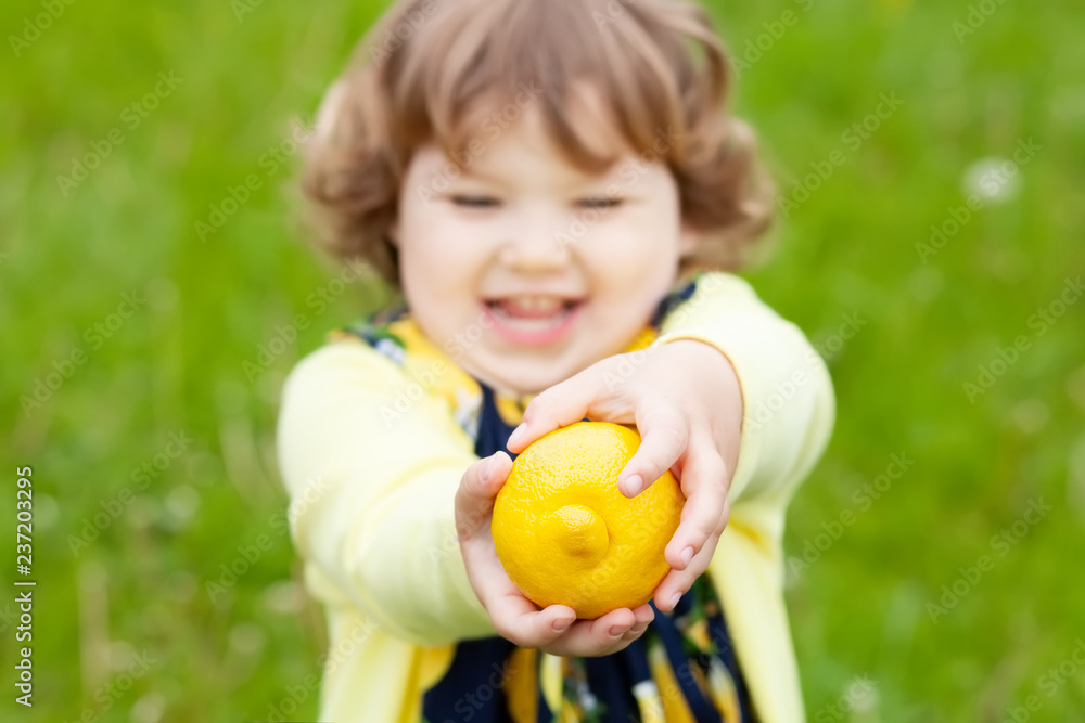 Funny little girl with lemon fruit outdoors