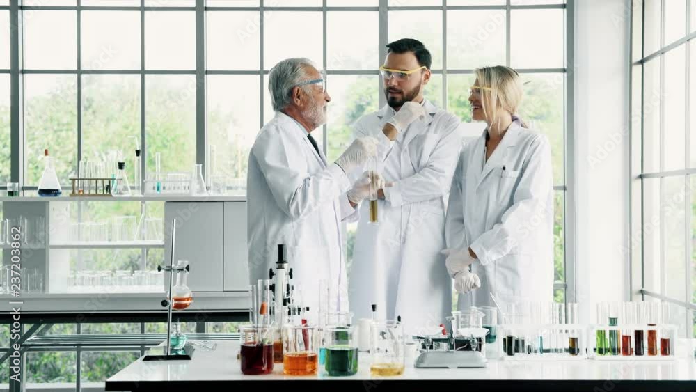 Group of chemists working in a lab. Young white male and female chemists with senior caucasian chemist working together in lab, discussing work. Science concept. Group of chemists working in a lab. Young white male and female chemists with senior caucasian chemist working together in lab, discussing work. Science concept.