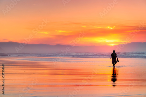lonely person walking on beach at beautiful red sunset