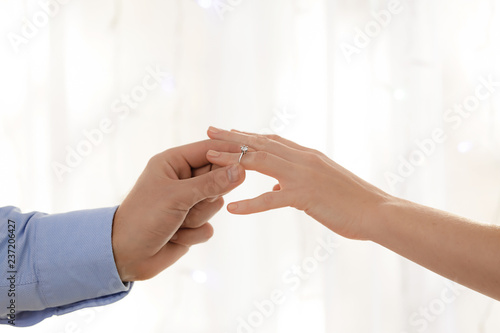 Young man putting engagement ring on fiancee's finger