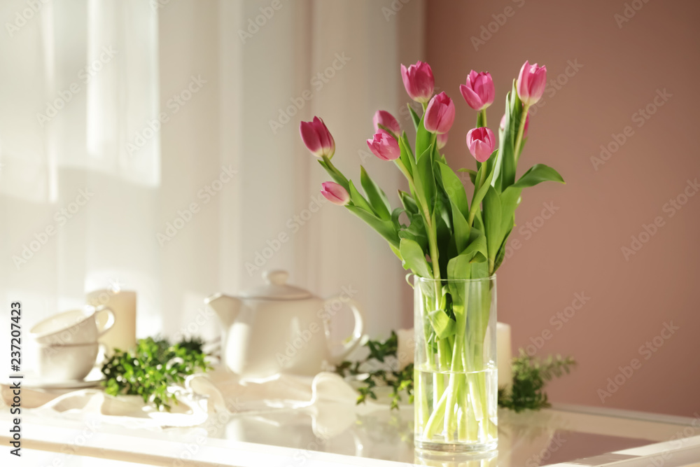Vase with beautiful tulips on glass table Vase with beautiful tulips on glass table