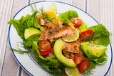 Delicious  salad of  fried  trout, avocado,  tomatoes and herbs at plate