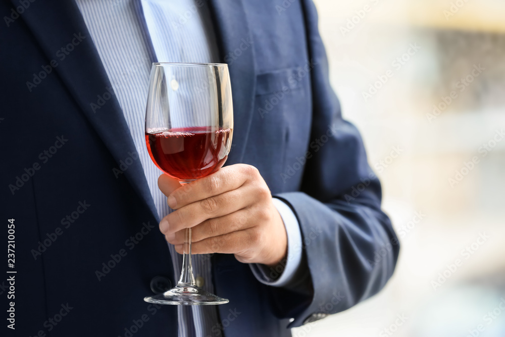 Businessman drinking wine near window, closeup Businessman drinking wine near window, closeup