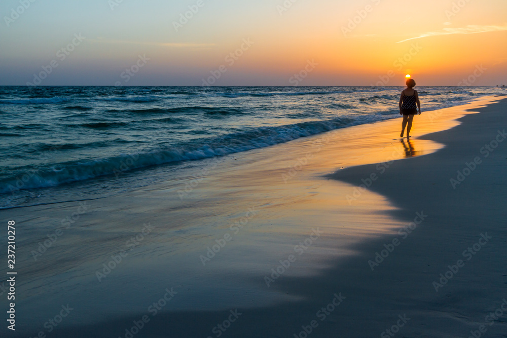 Woman walking on the beach at sunset