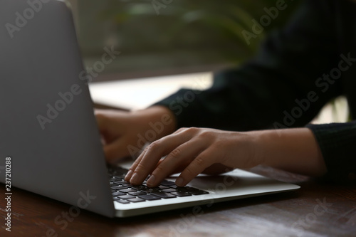 Woman using computer at wooden table, closeup