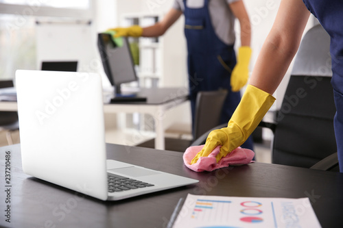 Janitor wiping table in office