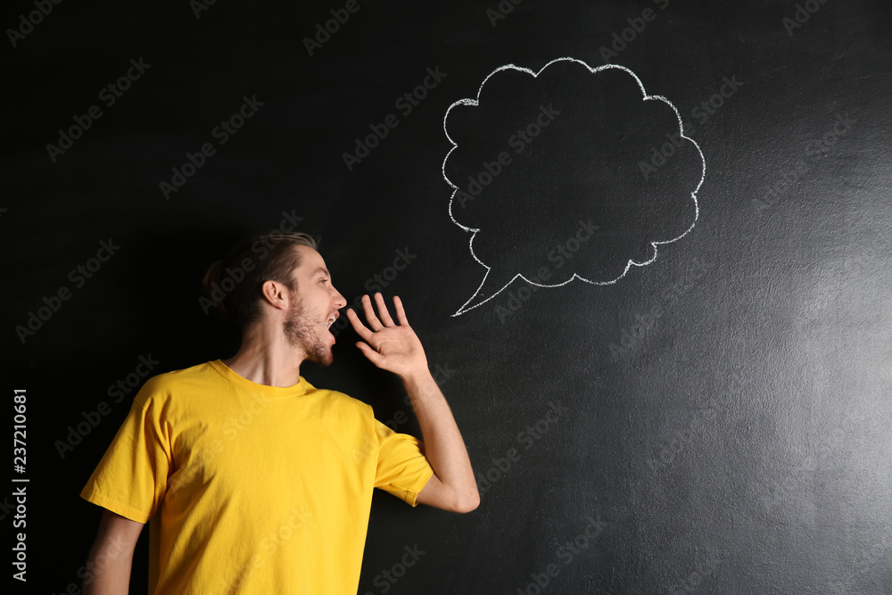 Screaming young man and blank speech bubble drawn on dark background Screaming young man and blank speech bubble drawn on dark background