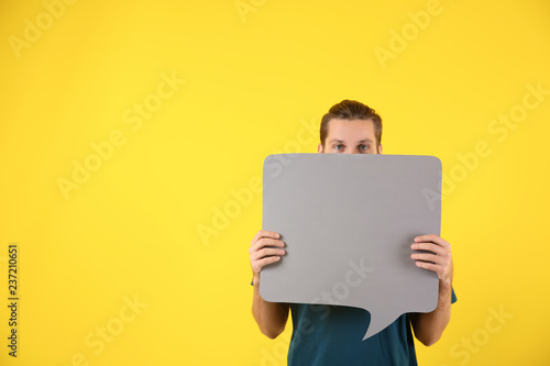 Young man with blank speech bubble on color background
