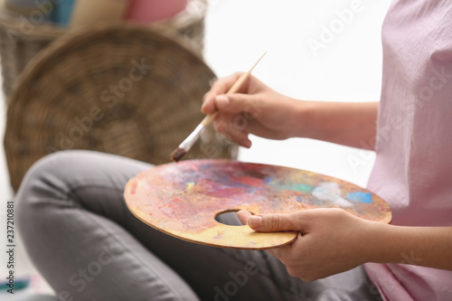 Young woman with palette and paintbrush, closeup