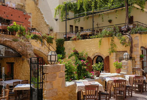 Patio in a Greek tavern with arches, stairs, plants and lanterns. Chania, Crete, Greece.