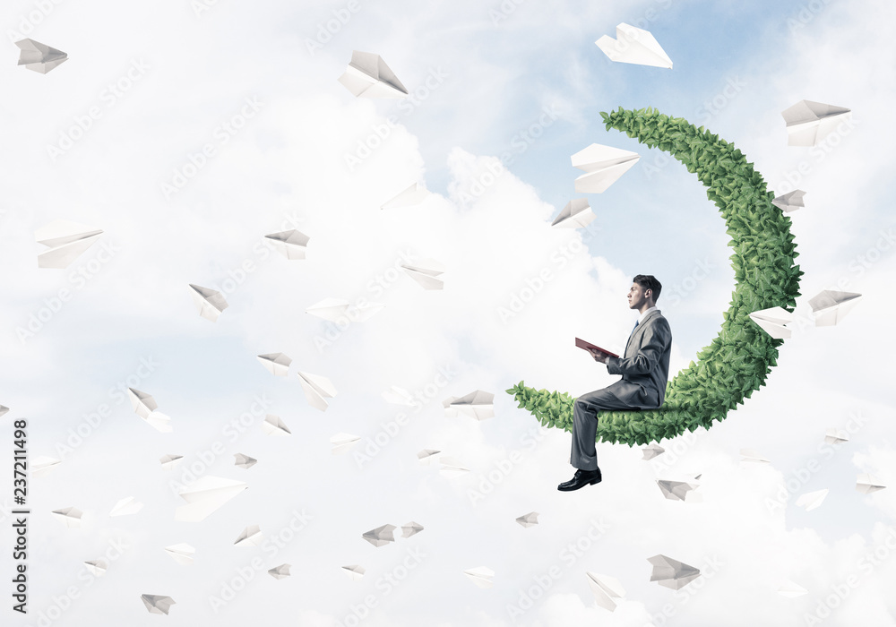 Businessman or student sitting on green moon and reading book Businessman or student sitting on green moon and reading book