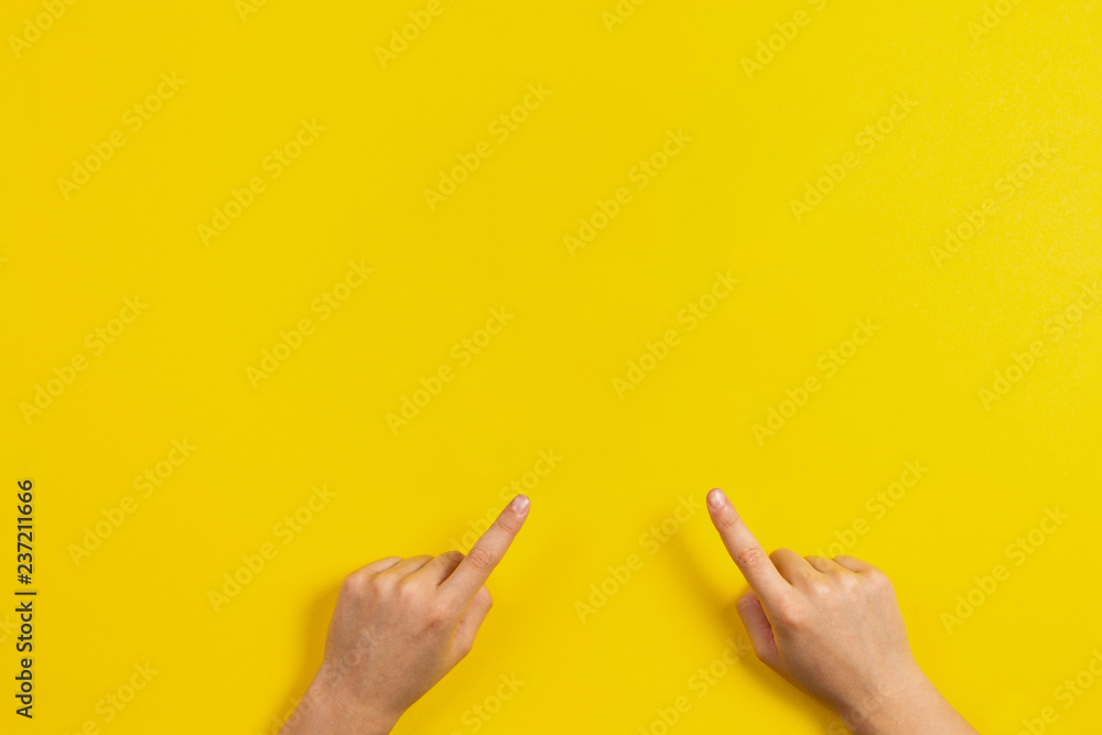 Kid hands pointing to something on yellow background Kid hands pointing to something on yellow background