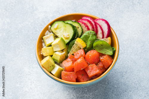 Traditional Hawaiian Poke salad with salmon, avocado rice and vegetables in a bowl.