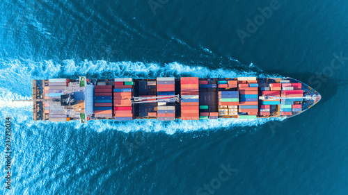 Aerial top view full speed container ship in the sea for logistics import export, shipping or transportation concept.