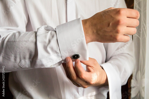 Male hand buttons cufflinks on the sleeve.
