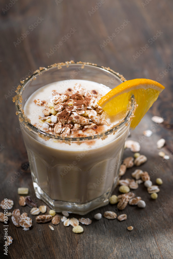 creamy cocktail with oats on dark background, vertical top view creamy cocktail with oats on dark background, vertical top view