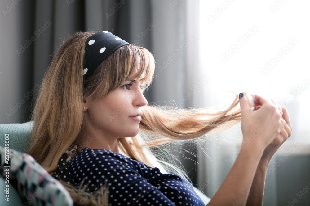 Fototapeta premium Woman at home looking at her hair, checking hair condition